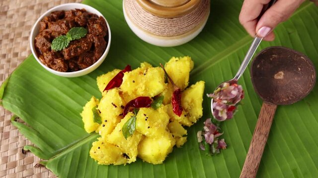 Cooked tapioca Cassava root Kappa with spicy meat beef pork curry Mandioca Aipim Indian food woman hand serving on banana leaf 4K video footage. South Indian food Asian cuisine Kerala India Sri Lanka