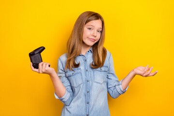 Photo of unsure teen brown hairdo girl hold playstation wear denim shirt isolated on bright yellow...