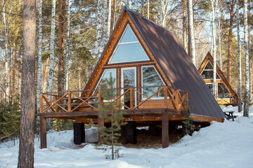 Contemporary country house standing in snow in the forest in front of camera on background of other...