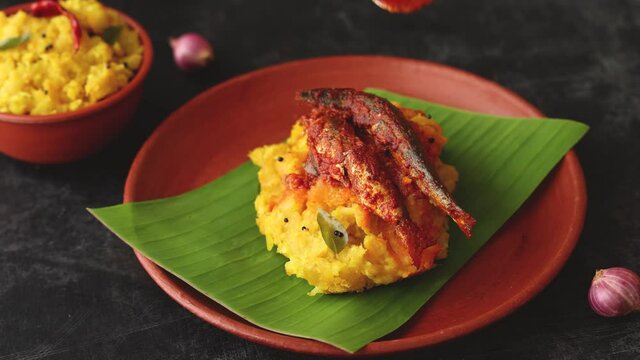 tapioca and spicy hot Kerala fish curry Indian food on banana leaf 4K video footage. Kappa sardine masala fish curry. Asian cuisine Bengali macher Jhal Goan fish curry in coconut milk cassava 