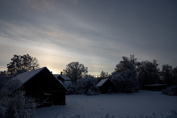 underexposed black village houses under beautiful sunset sky in wintertime in Latvia