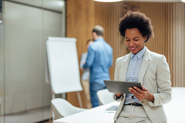 Smiling african-american woman, the software on her tablet before meeting.