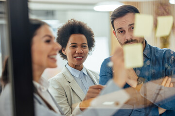 Experienced caucasian woman, giving pointeres to her colleagues via notes.