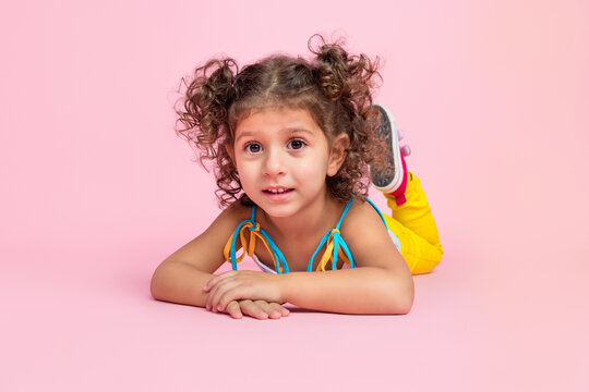 Portrait of attractive cheerful wavy-haired girl lying on floor resting summer time isolated over pink pastel color background