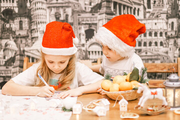 very beautiful children in a cute Santa hat write a letter to Santa Claus during the Christmas and New Year holidays