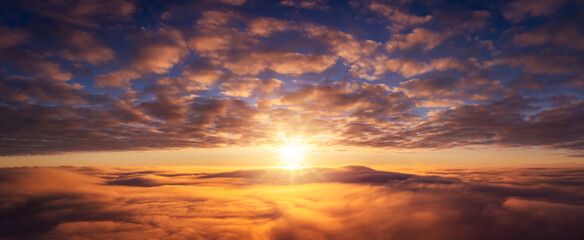 Fototapeta na wymiar Wide panorama of setting sun above the clouds. Vibrant cloudscape of sun going under horizon
