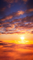 Naklejka na ściany i meble Vertical 9:16 photo of setting sun above the clouds. Beautiful vibrant background of heaven-like sky