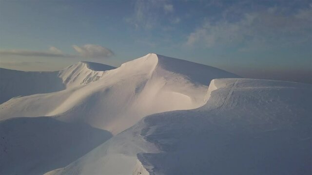 Aerial view of mountain snow-capped peak, at sunrise