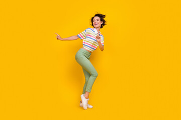 Fototapeta na wymiar Full size photo of cool young brunette lady dance wear t-shirt trousers shoes isolated on yellow color background