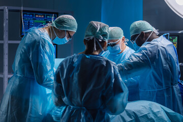 Multiracial team of professional medical surgeons performs the surgical operation in a modern...