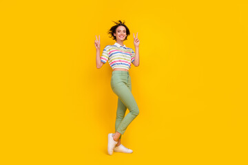 Fototapeta na wymiar Full size photo of young girl happy positive smile show peace cool v-sign isolated over yellow color background