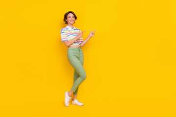 Fototapeta na wymiar Full size photo of young girl happy positive smile point fingers empty space ad choice follow isolated over yellow color background