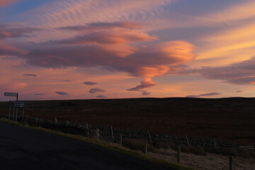 Lenticular clouds over moorland road in Northumberland, UK