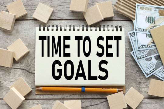 time to set goalos. the text on the notebook that lies on the working wooden table near the wooden blocks