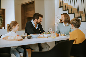 Young happy family talking while having breakfast at dining table