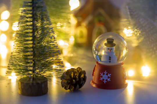 Snow man in globe with small house and pine trees background