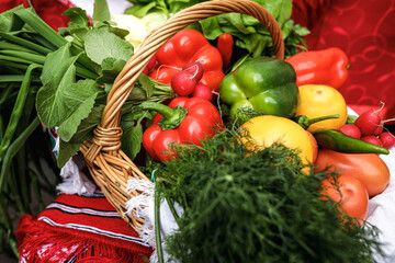 Shallow depth of field (selective focus) image with a basket filled with organic fresh vegetables (red pepper, radish, spring onion, tomatos) for sale in an outdoors market in Bucharest, Romania.