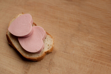 sausage sandwich in the form of hearts on a blurred wooden background