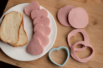 preparation for making sausage sandwiches in the form of hearts on a wooden background