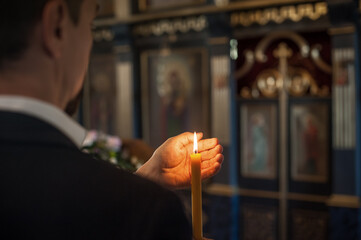 Hands closeup of religious man holding lit candle and praying