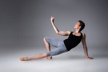 graceful dancer performing ballet dance on dark grey background