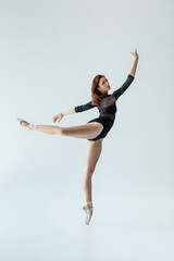 Fototapeta na wymiar full length of ballerina in black bodysuit performing dance isolated on grey