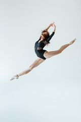 Fototapeta na wymiar full length of ballerina in black bodysuit jumping isolated on grey