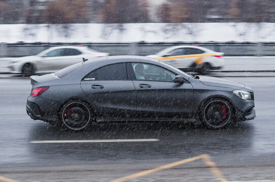 fast moving Mercedes CLA rides on a winter city road. Mercedes-Benz CLA 200 car on wet slippery road in motion. Overspeed in city concept