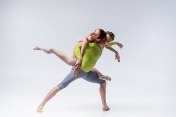 full length of strong ballet dancer lifting graceful ballerina on grey © LIGHTFIELD STUDIOS