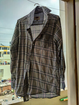 Stock photo of gray rhino color full sleeves cheks shirt hanging on hanger and drying in the house balcony at bangalore, Karnataka, India. Picture captured during sluggish climate. selective focus.
