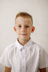 Fototapeta premium A boy in a white shirt plays checkers while sitting at a desk.