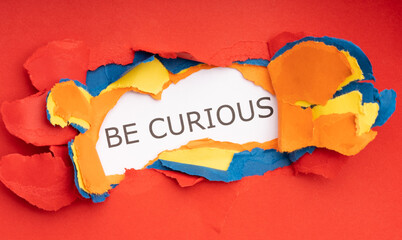 Construction paper of different colors torn to make a hole that uncovers the phrase "Be Curious"