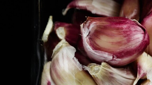 Close up of garlic cloves rotating in the glass.