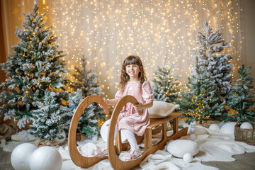 A child on a sled among the trees in the New Year's decorations.