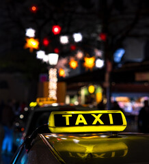 german taxi sign, illuminated by night with city lights in background