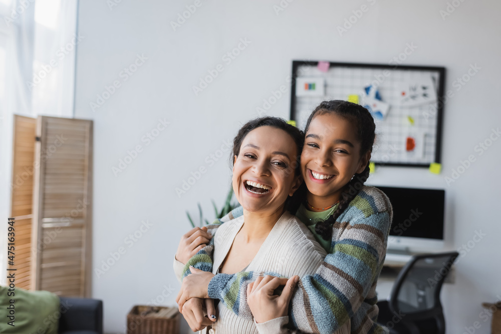 Wall mural excited african american girl embracing mother while looking at camera