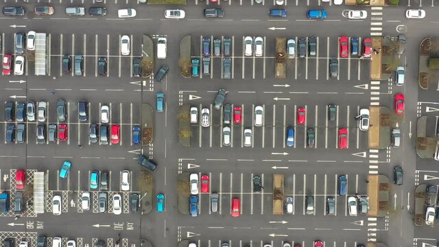 Aerial footage above a busy car park taken in the winter time in the town of Colton in Leeds West Yorkshire UK, showing a busy car park with cars looking for parking spaces