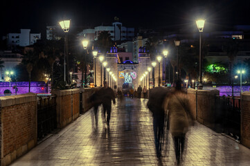 Obraz premium Puerta Palma, Badajoz illuminated with Christmas lighting, end of the year 2021, new year 2022 in Badajoz, people walking on the bridge