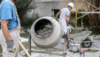 Labore worker operating concrete cement mixer at construction site.