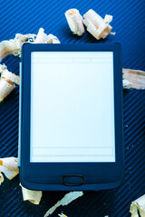Replacing paper books with electronic ones.E-book and wood shavings. Tablet and wood. Open e-book.