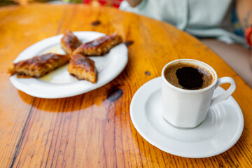 Coffee and sweet Turkish dessert baklava on a table in a rustic simple cafe