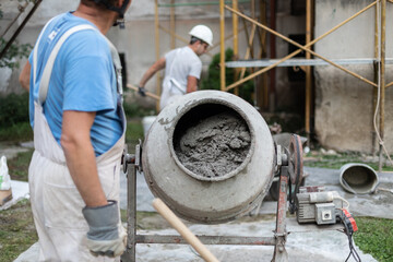 Labore worker operating concrete cement mixer at construction site.