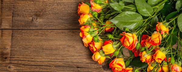 Bouquet of bright yellow-orange roses on old wooden table