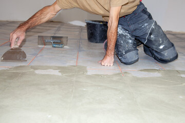 Construction worker leveling compound with putty knife. Renovation, floor leveling screed, mass...