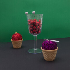 New Year's balls in cones and decoration in a glass on a black green background with copy space. Minimalistic scene.