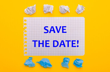 On a yellow background, white and blue crumpled pieces of paper and a notebook with the text SAVE THE DATE