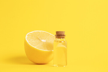Serum with vitamin C. Lemon essential oil. Glass bottle with a pipette, half a lemon on yellow background. Great fermented ingredient.Health and beauty concept. Organic natural cosmetics.
