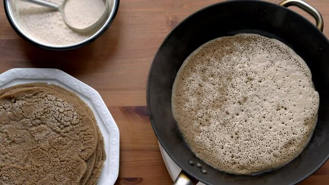 Injera traditional Ethiopian sourdough ferment flatbread preparation. Making injera food from teff flour on pan.