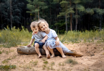 Cute little children sitting on a log on a forest background