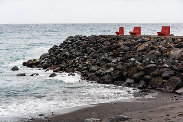 Red stone benches on rocks on volcanic beach. Tenerife, Canary islands